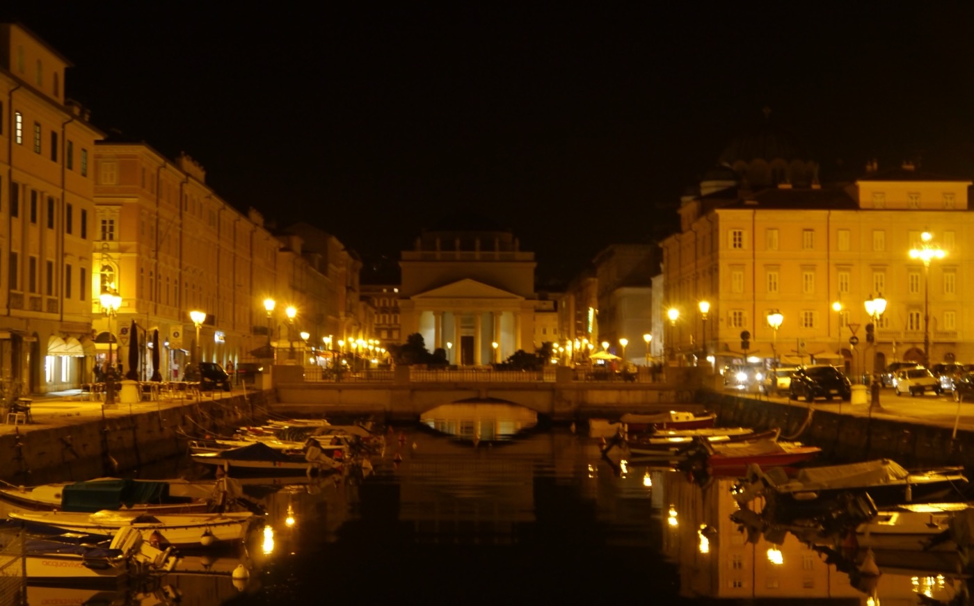 Il Canal Grande di Trieste di notte, con la chiesa di Sant'Antonio Nuovo illuminata sullo sfondo e le barche ormeggiate